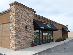 A pizza restaurant with brick walls and black awnings.