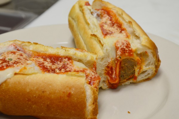A meatball sandwich with marinara sauce and cheese.