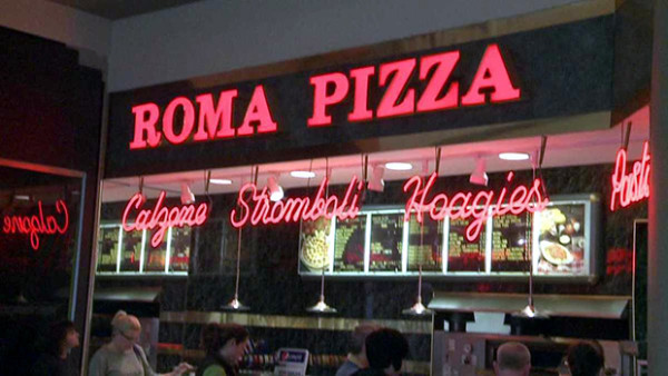 A pizza restaurant with neon lights and people sitting at tables.